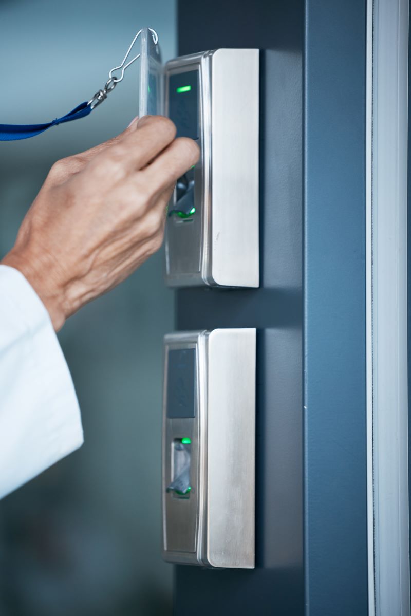 A woman waves a keycard over a proximity reader to open a door